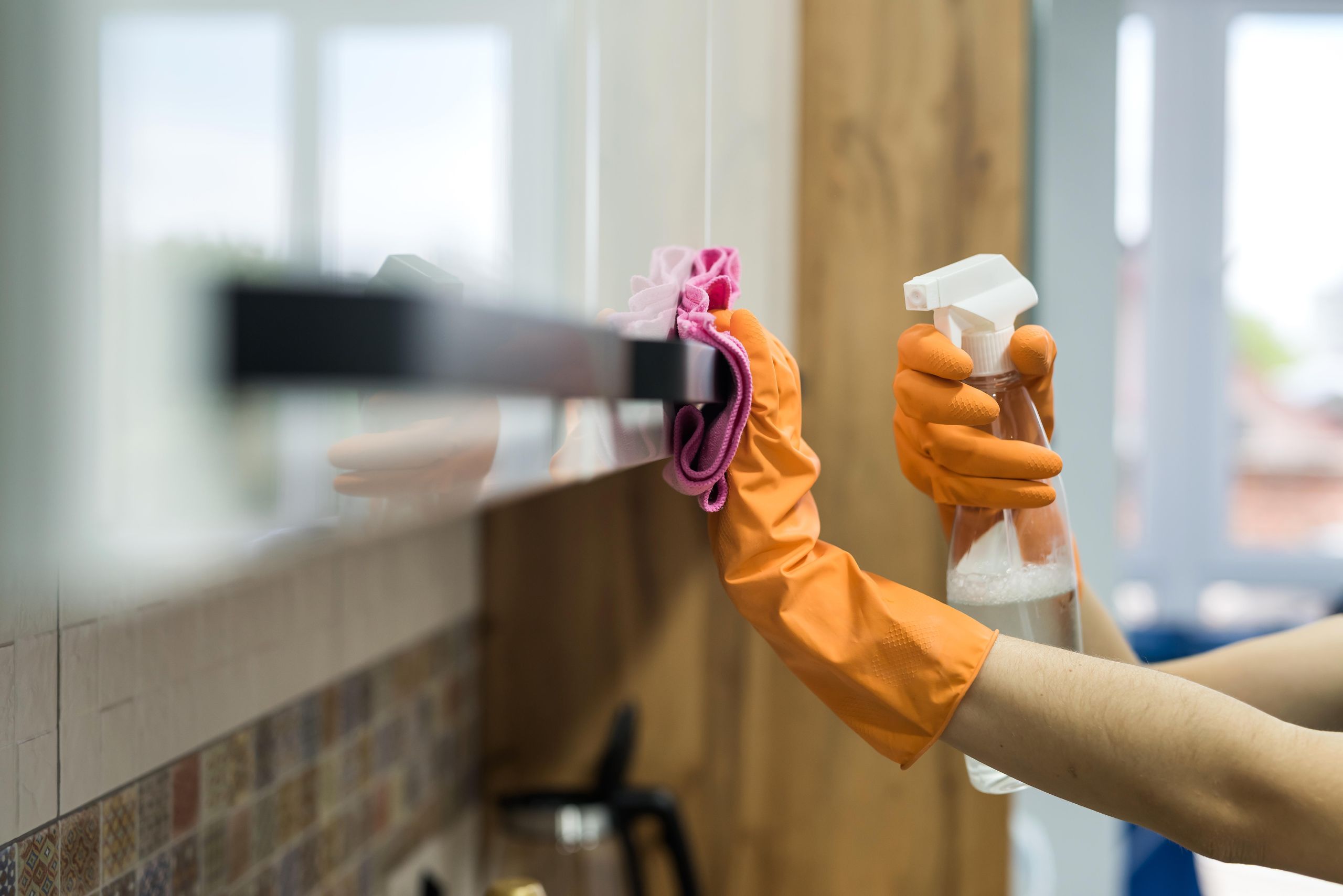 Cleaner wiping a kitchen cabinet during time-based service